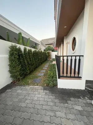 a house with a brick walkway next to a building at Falisa House Apartment Bangtao in Ban Thalat Choeng Thale