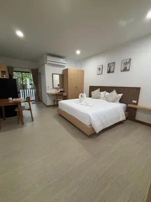 a bedroom with a large white bed and a desk at Falisa House Apartment Bangtao in Ban Thalat Choeng Thale