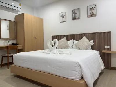 a bedroom with a white bed with a white ribbon on it at Falisa House Apartment Bangtao in Ban Thalat Choeng Thale