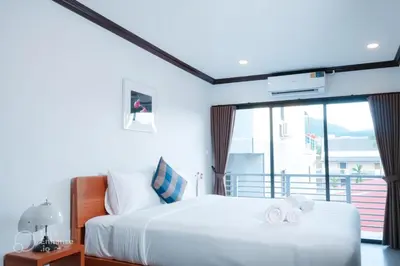 a bedroom with a white bed and a large window at Oh'tel Kata in Kata Beach