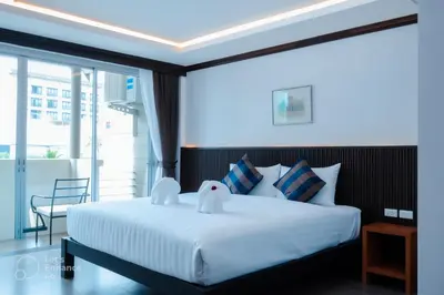 a bedroom with a large white bed and a balcony at Oh'tel Kata in Kata Beach