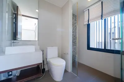 a bathroom with a toilet and a sink and a window at Friendly Lux 5 Bedroom Villa Laguna park in Laguna Phuket