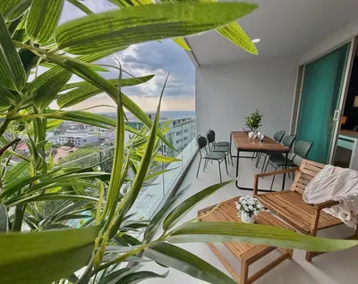 a room with a balcony with tables and chairs at Family apartment 2-BR with Sea View - Karon Beach in Ban Karon