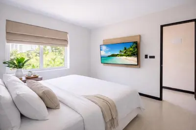 a white bedroom with a large bed and a window at Santosa Hotel & Welness Center in Ban Kata
