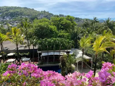 a view of a resort with palm trees and purple flowers at Beachfront 2 BR Luxury Condominium Surin in Surin Beach