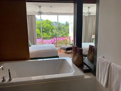 a bathroom with a tub and a large mirror at Beachfront 2 BR Luxury Condominium Surin in Surin Beach