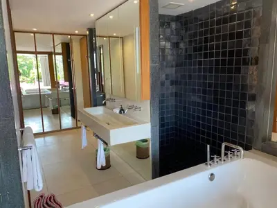 a bathroom with a tub and a sink and a mirror at Beachfront 2 BR Luxury Condominium Surin in Surin Beach