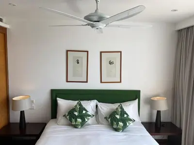 a bedroom with a white bed with a ceiling fan at Beachfront 2 BR Luxury Condominium Surin in Surin Beach