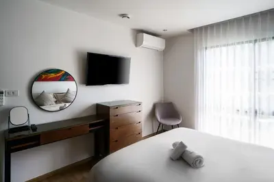 a bedroom with a bed and a desk and a mirror at The Title Condo 2BR by G Estate Phuket in Phuket Town
