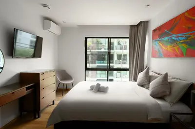 a bedroom with a bed with a dresser and a window at The Title Condo 2BR by G Estate Phuket in Phuket Town