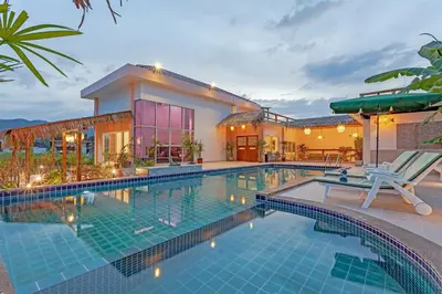 a swimming pool in front of a house at Tom Star Pool Villa Layan in Thalang