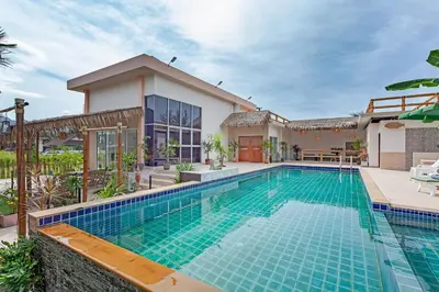 a swimming pool in front of a house at Tom Star Pool Villa Layan in Thalang