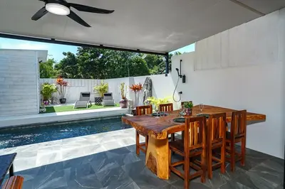 a dining room with a table and chairs and a pool at Lili Villa by G Estate Phuket in Nai Harn Beach