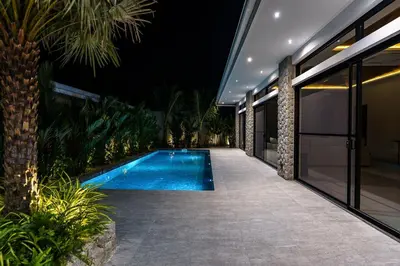a swimming pool in front of a house at night at Ramon Villa by G Estate Phuket in Ban Saiyuan (1)