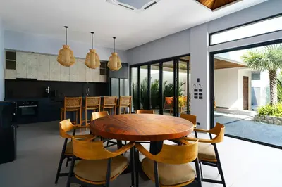 a kitchen and dining room with a wooden table and chairs at Ramon Villa by G Estate Phuket in Ban Saiyuan (1)