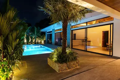 a house with a swimming pool and a palm tree at Ramon Villa by G Estate Phuket in Ban Saiyuan (1)