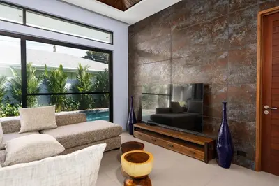 a living room with a couch and a large window at Ramon Villa by G Estate Phuket in Ban Saiyuan (1)