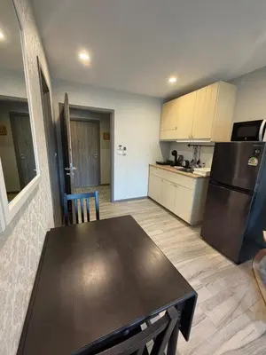 a kitchen with a table and a black refrigerator at 1 BDR 5 Swimming Pool Entire Condo 5 Mins Walk To Naiyang Beach in Nai Yang Beach