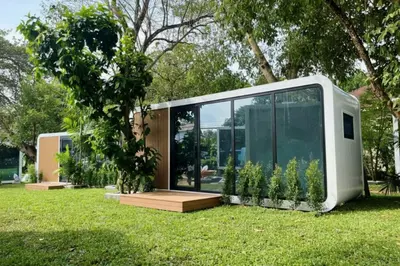 a small house with glass doors on the grass at NeOtel Apartments in Ban Saiyuan (1)
