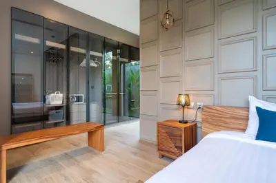 a bedroom with a bed and a bench and glass walls at Cocoon Villa 6 - Eden Escape 3 BR - Pool - Garden in Ban Sakhu