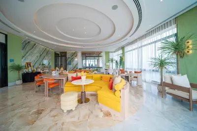 a living room with a yellow couch and tables and chairs at Canvas Cherngtalay Holiday Apartments in Laguna Phuket