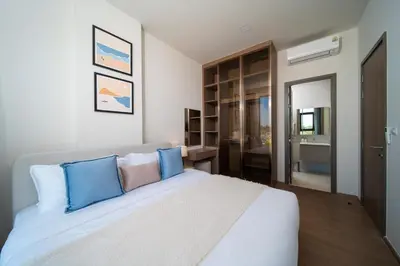 a bedroom with a large white bed with blue pillows at Canvas Cherngtalay Holiday Apartments in Laguna Phuket