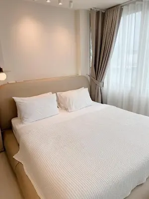 a white bed with white pillows and a window at Breeze House Patong in Patong Beach