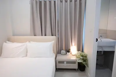a white bedroom with a bed and a sink at Breeze House Patong in Patong Beach