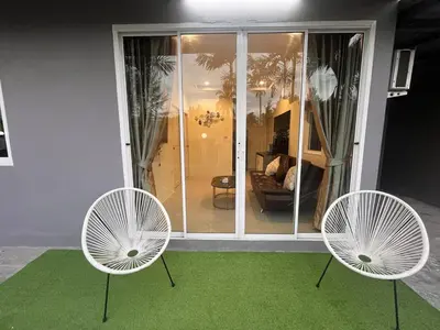 two white chairs and a green rug in a room at Cozy 2-Bedroom Place in a Quiet Area Nearby Beach in Ban Lum Fuang