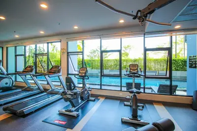 a gym with cardio machines and a swimming pool at Vista Residence Old Town in Phuket Town