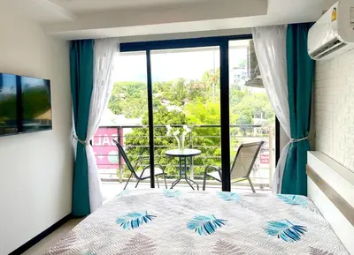 a bedroom with a bed and a balcony with a table at Rawai Beach Condom in Ban Saiyuan (1)