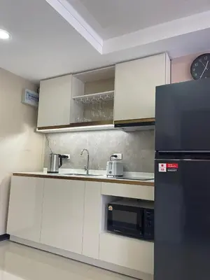 a kitchen with white cabinets and a black refrigerator at Rawai Beach Condom in Ban Saiyuan (1)