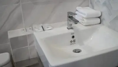 a white bathroom sink with towels on top of it at Tiny house bangtao phuket in Ban Thalat Choeng Thale