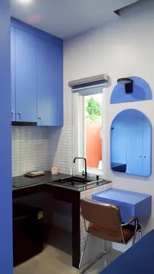 a kitchen with blue cabinets and a sink and a chair at Tiny house bangtao phuket in Ban Thalat Choeng Thale