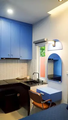 a kitchen with blue cabinets and a sink and a chair at MSP house bangtao in Ban Thalat Choeng Thale