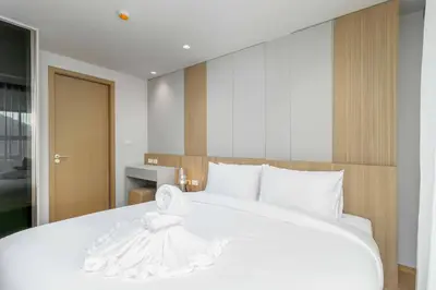 a large white bed with a white dress on it at C263 Brand New Condo Near Lake & Nai Harn Beach in Rawai Beach