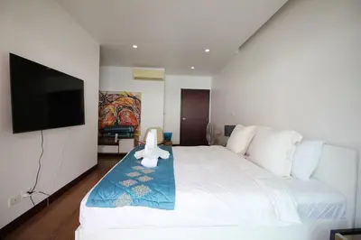 a bedroom with a white bed and a flat screen tv at Modern 3BR Townhouse Kamala in Kamala Beach