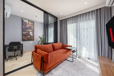 a living room with an orange couch and a desk at Vela 1BR Suite — The Title Legendary BangTao in Bang Tao Beach