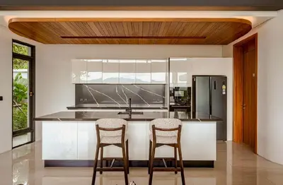 a kitchen with two bar stools and a refrigerator at Zavaya Luxury Villa by 87Homes in Layan Beach