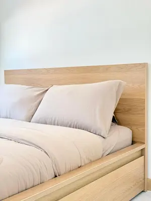 a bed with white sheets and a wooden headboard at Harmony House in Ban Bang Khu