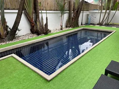 a swimming pool with blue tiles on the grass at Euphoria Property in Kamala Beach