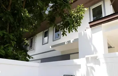a white building with trees in the foreground at Euphoria Property in Kamala Beach