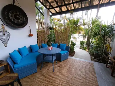 a patio with blue couches and a table and plants at Studio in Phuket Nai Harn in Rawai Beach