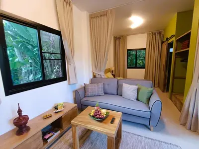 a living room with a blue couch and a table at Studio in Phuket Nai Harn in Rawai Beach