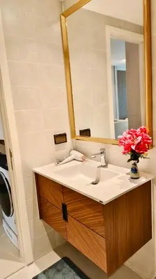 a bathroom with a sink with a mirror and a vase of flowers at Luxury 2 Person Apartment in Heart of Phuket 2 in Ban Ket Ho