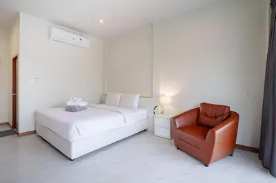 a white bedroom with a bed and a chair at 1 bedroom apartment - 2 min to the Nai Harn beach in Rawai Beach