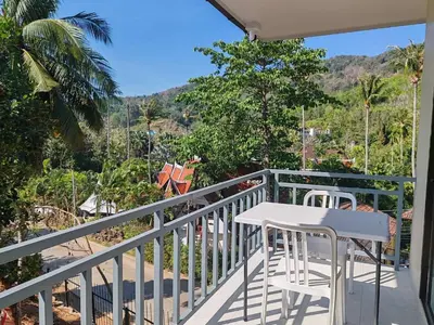 a balcony with a white table and chairs on it at 1 bedroom apartment - 2 min to the Nai Harn beach in Rawai Beach