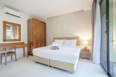 a bedroom with a large white bed and a desk at 1 bd Villa - 2 minutes to the Nai Harn beach A101, A102 in Rawai Beach