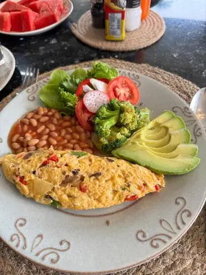 a plate of food with a omelet and beans and vegetables at Bell Seaside Residence in Rawai Beach
