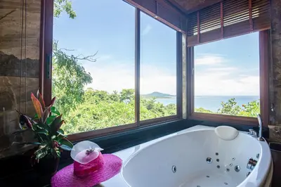 a bathroom with a bath tub with a large window at Bell Seaside Residence in Rawai Beach